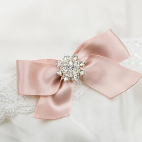 white lace garter with a champagne coloured bow and a diamante clustered centre