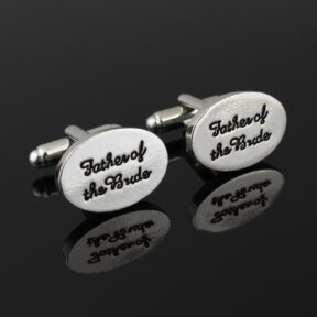 silver oval shaped cufflinks with father of the bride written in black cursive and debossed in the metal